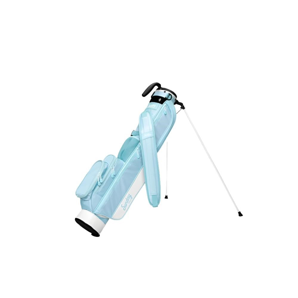 A light blue golf bag with a stand mechanism deployed, featuring multiple pockets and a shoulder strap.