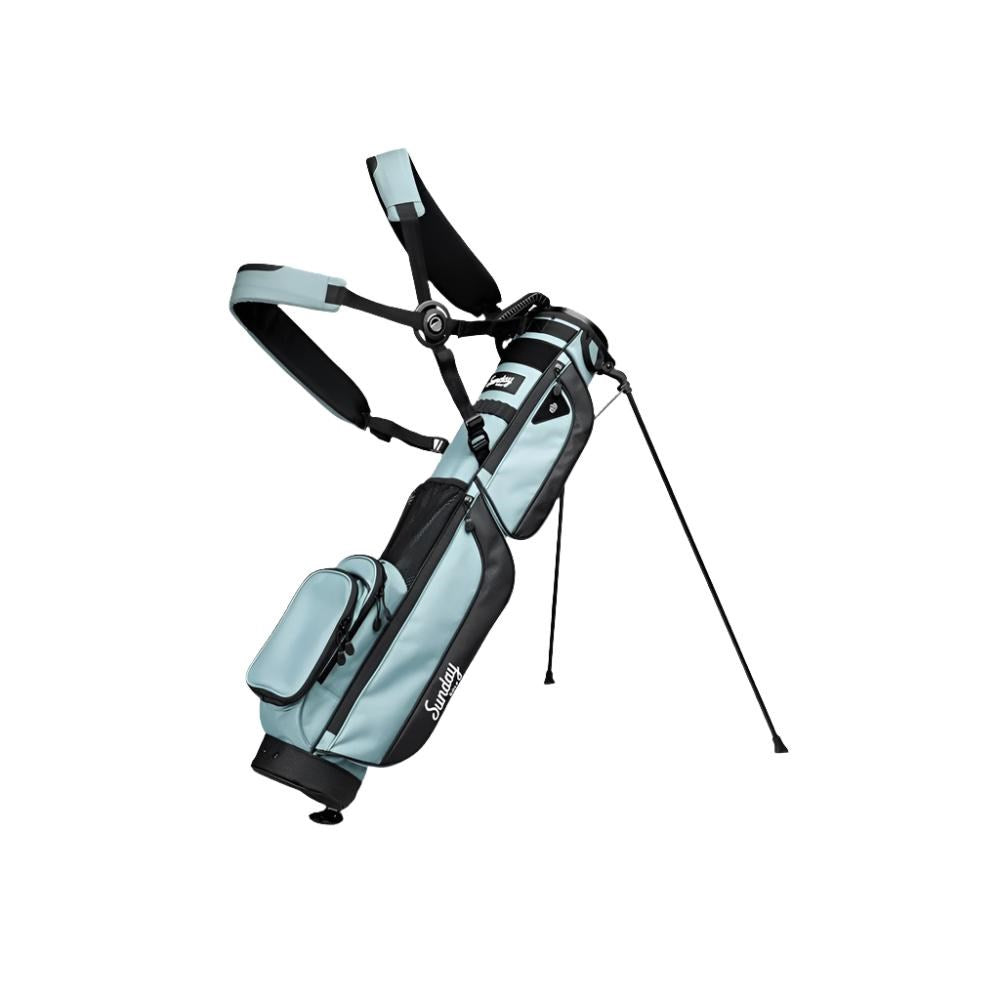 A light blue and black golf bag with a stand system deployed, featuring multiple pockets and a shoulder strap.
