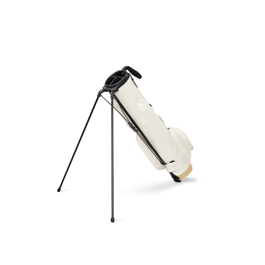 A beige and white golf bag with a stand system deployed, featuring multiple pockets