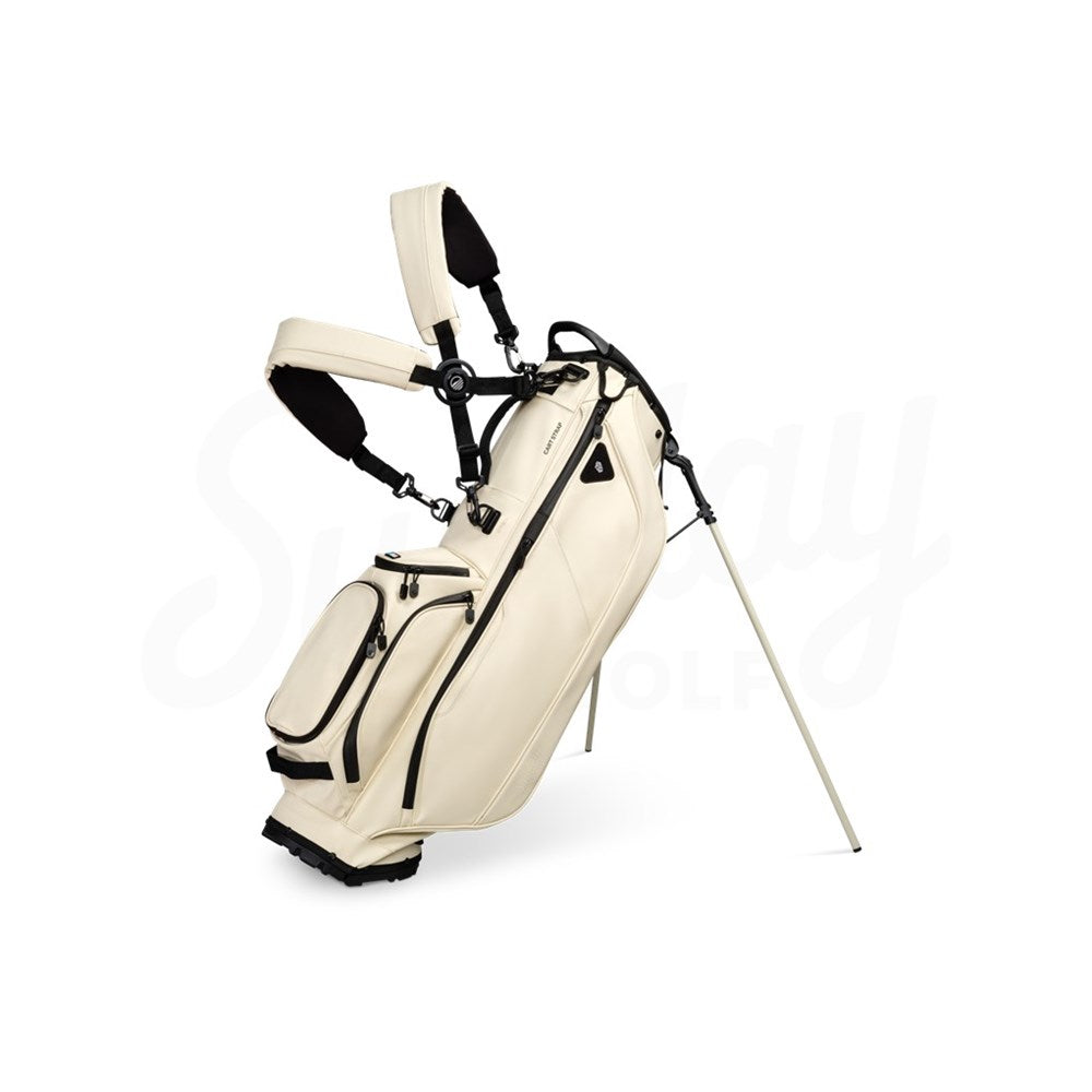 A beige Sunday Golf Ryder S-Class golf bag with a stand, featuring multiple pockets and a backpack-style strap system.