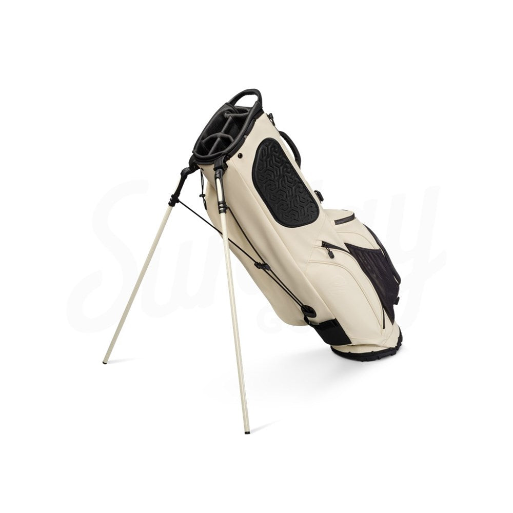 A beige Sunday Golf Ryder S-Class golf bag with a stand, featuring multiple pockets and a backpack-style strap system.