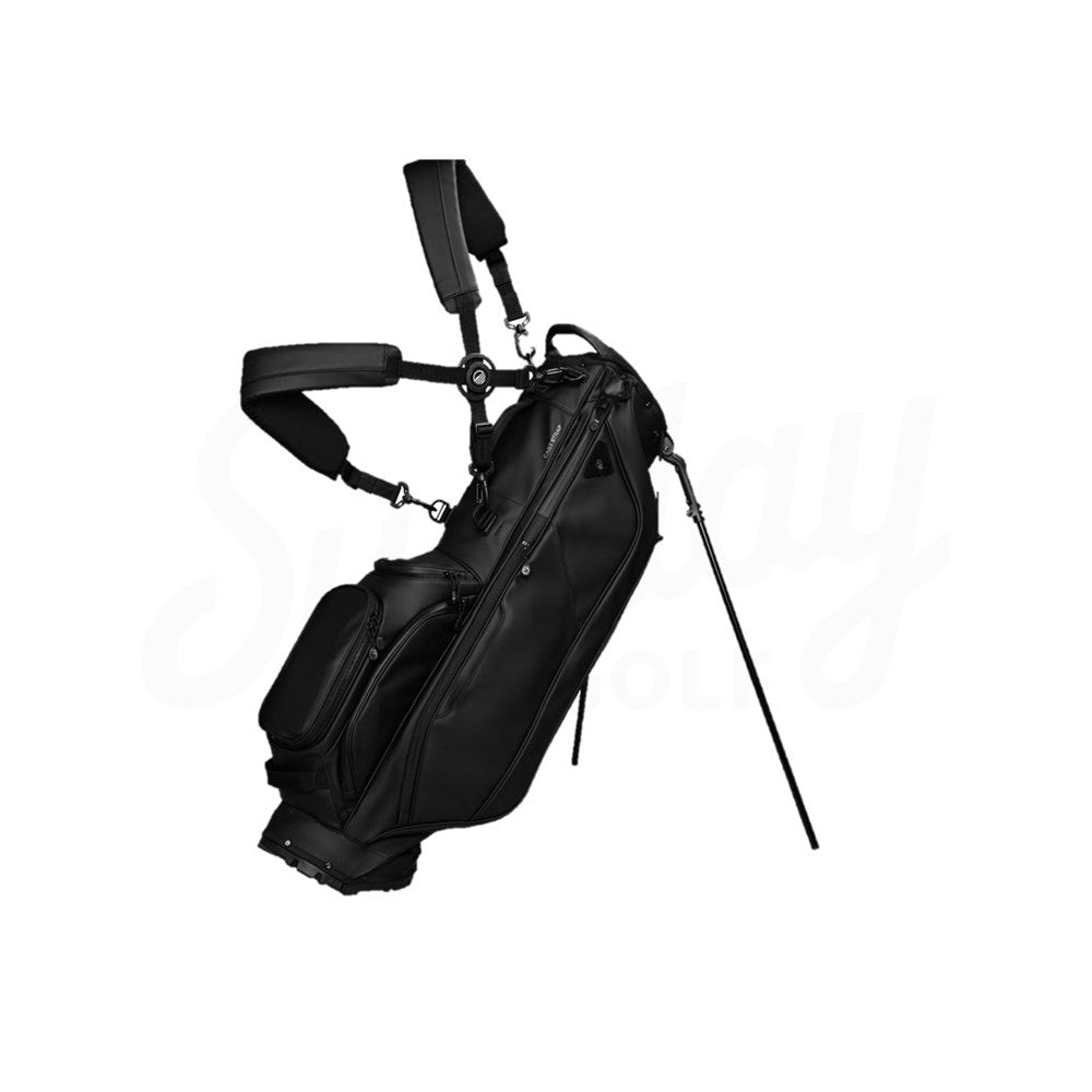 A black golf bag with backpack straps and a stand mechanism, featuring multiple pockets including an insulated one for drinks.