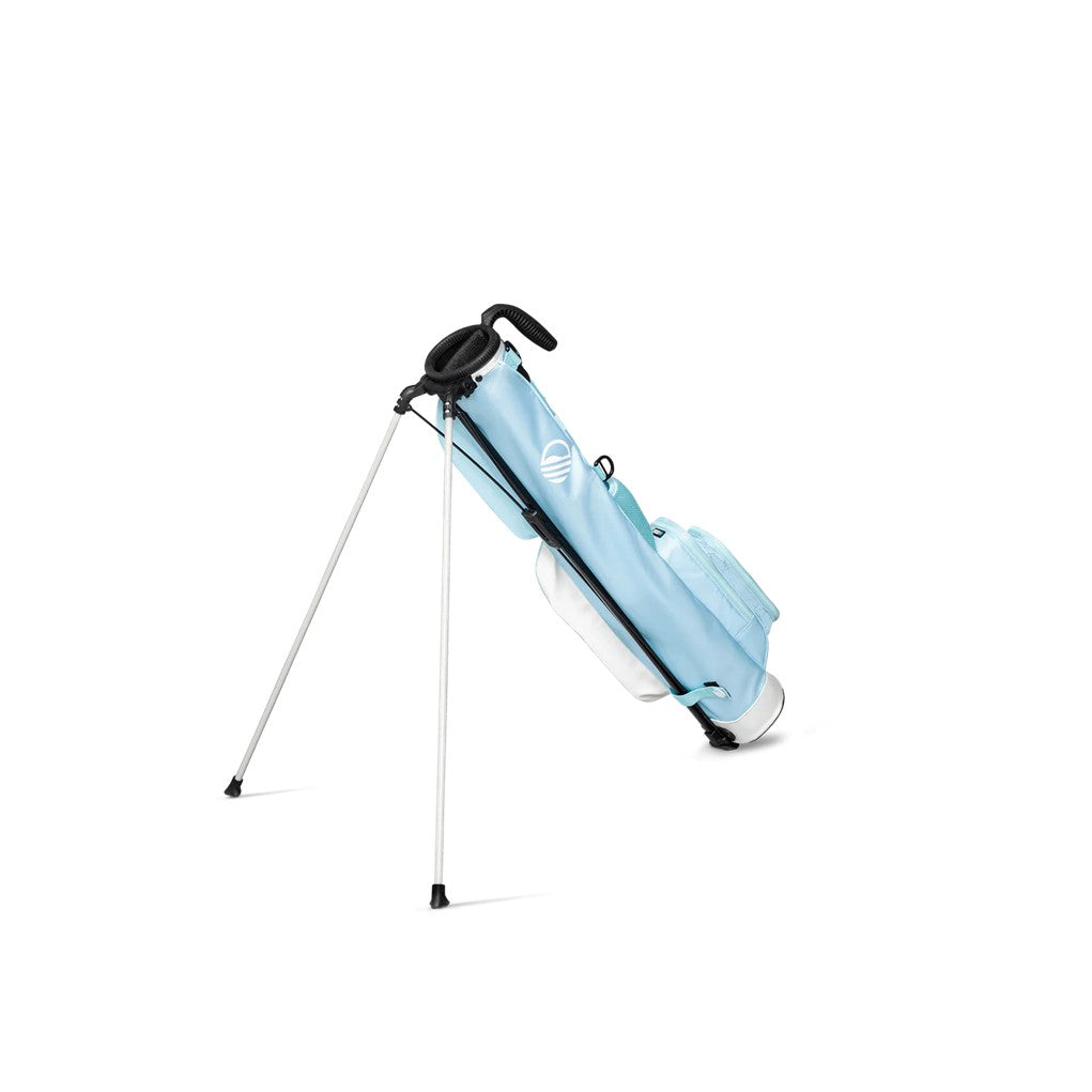 A light blue golf bag with a stand mechanism deployed, featuring multiple pockets and a shoulder strap.