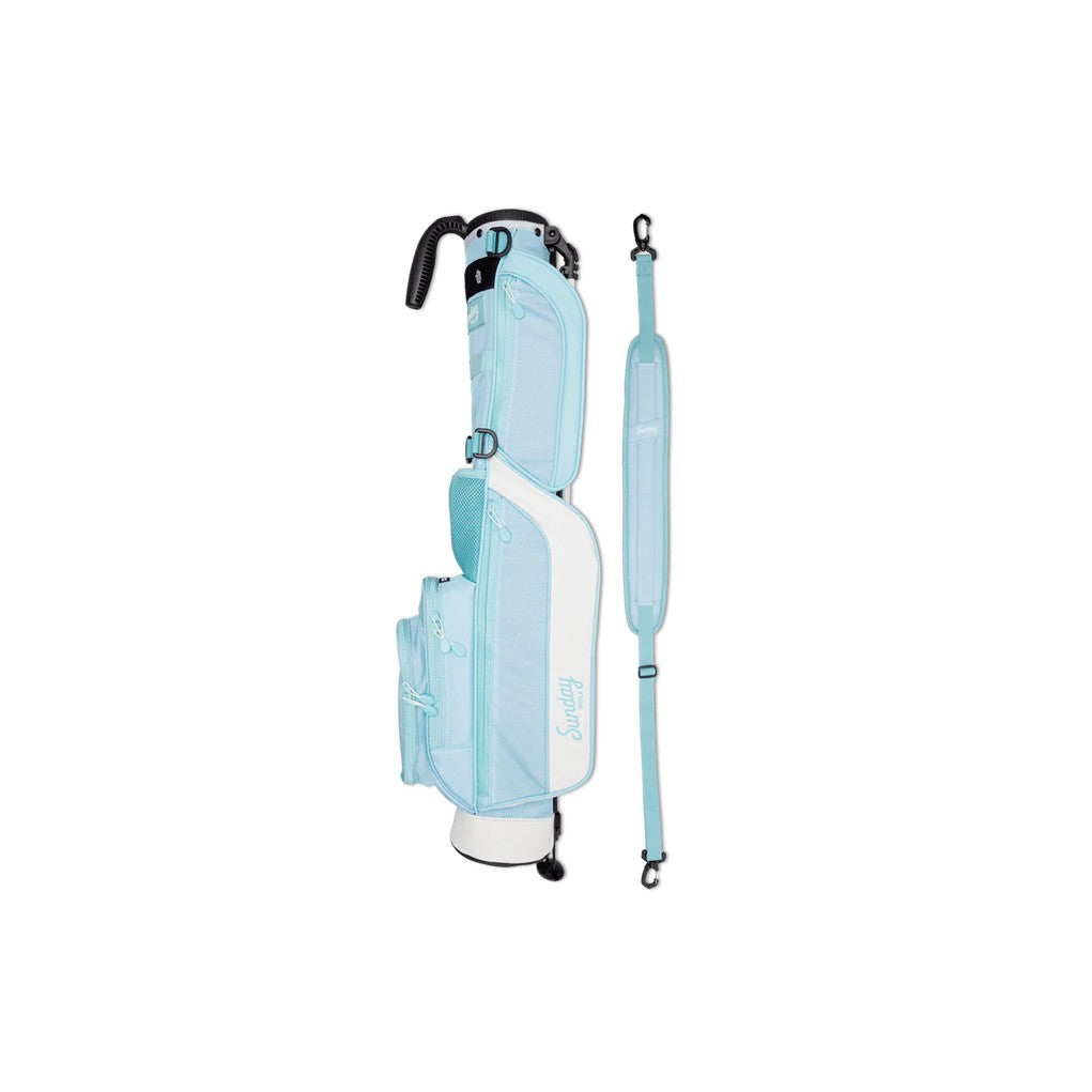 A light blue golf bag with a stand mechanism deployed, featuring multiple pockets and a shoulder strap.