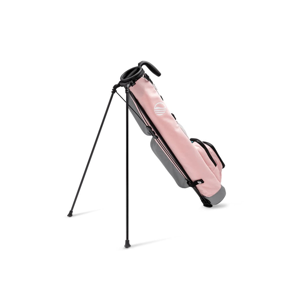 A pink and gray Sunday Golf range/green side golf bag with a stand, showing the front view with multiple pockets and a logo.