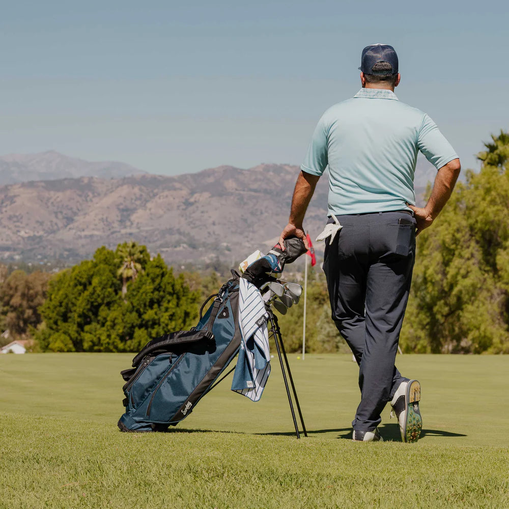 A full-size blue and black Sunday Golf stand bag with multiple pockets, a built-in carry handle, and backpack-style strap system. Back view